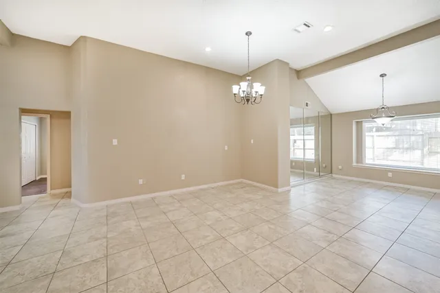 a view of an empty room with window and chandelier fan