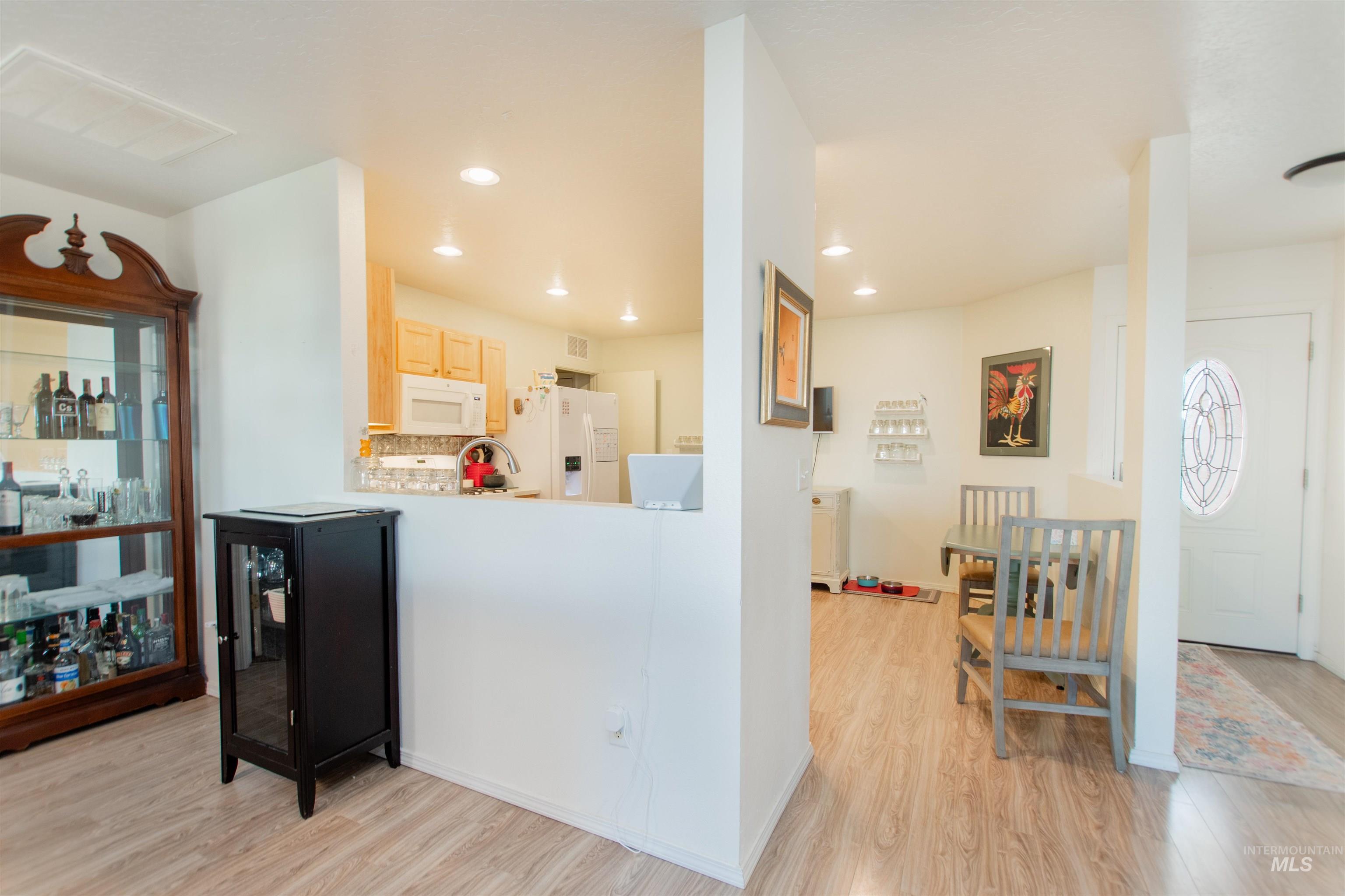 16711 Abram Avenue Caldwell, ID 83607 - Photo 4 of 24 Kitchen with light wood finish cabinets, light wood-type flooring, light countertops, white appliances, and decorative backsplash