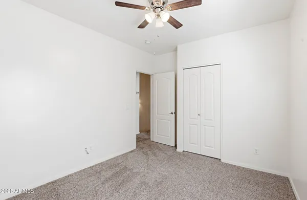 an empty room with closet and a ceiling fan