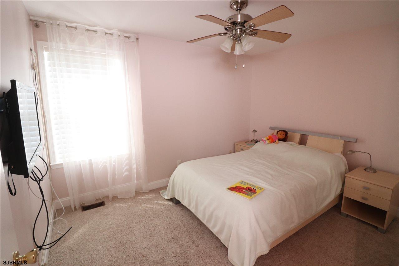 200 North Decatur Avenue, Unit 1 Margate City, NJ 08402 - Photo 10 of 12 a bedroom with a bed and a chandelier