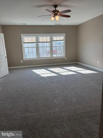 an empty room with chandelier fan and windows
