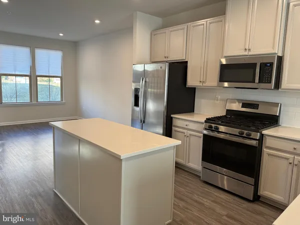 a kitchen with stainless steel appliances a stove a microwave and a hard wood floors