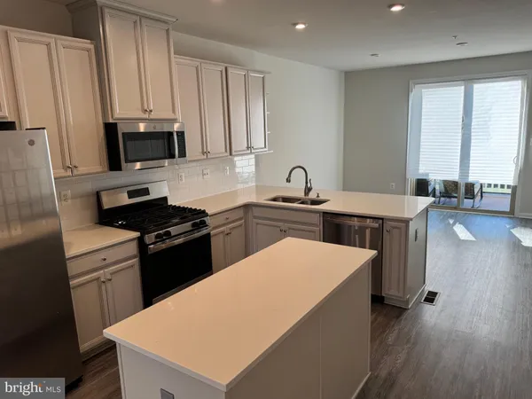 a kitchen with stainless steel appliances a sink stove refrigerator and cabinets