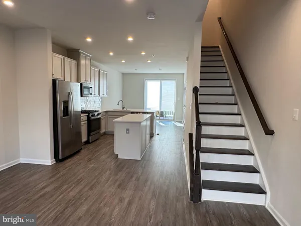 a kitchen with stainless steel appliances a refrigerator and wooden floor