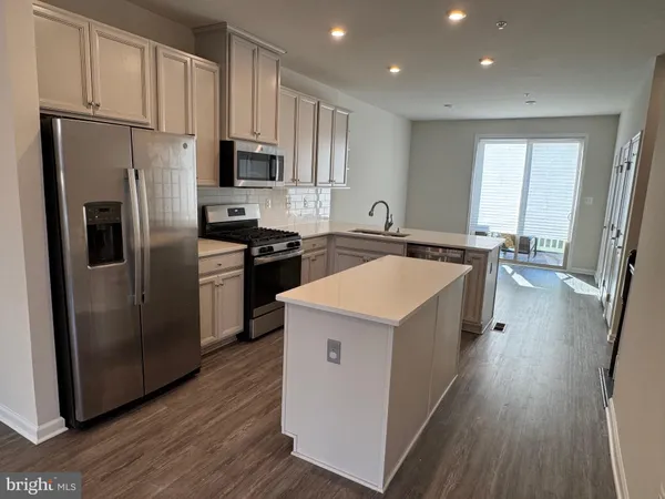 a kitchen with a refrigerator a sink dishwasher and a stove with wooden floor