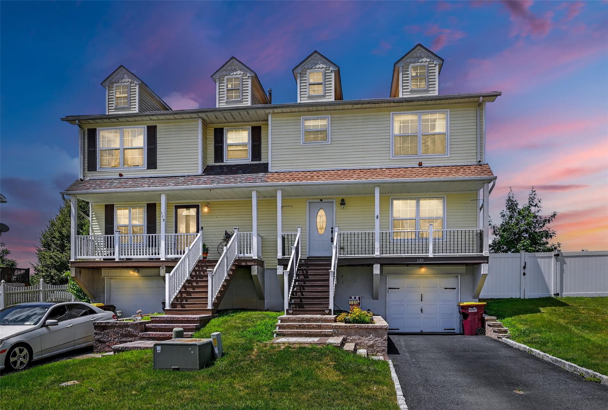 View of front facade with an attached garage, stairs, covered porch, a gate, and driveway