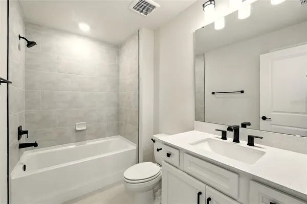 a bathroom with a sink a toilet a mirror a bathtub and shower