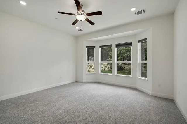 an empty room with a ceiling fan and windows