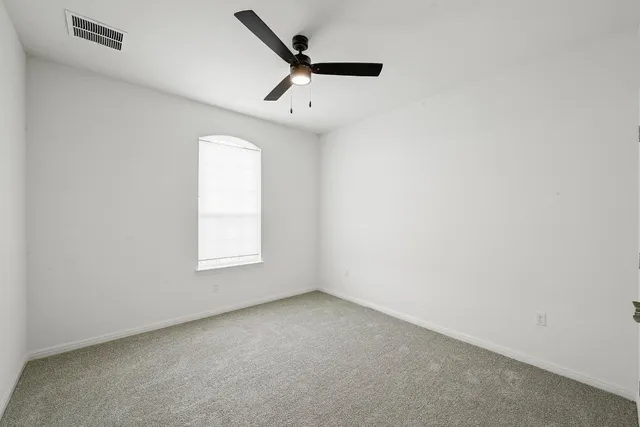 an empty room with a window and a ceiling fan