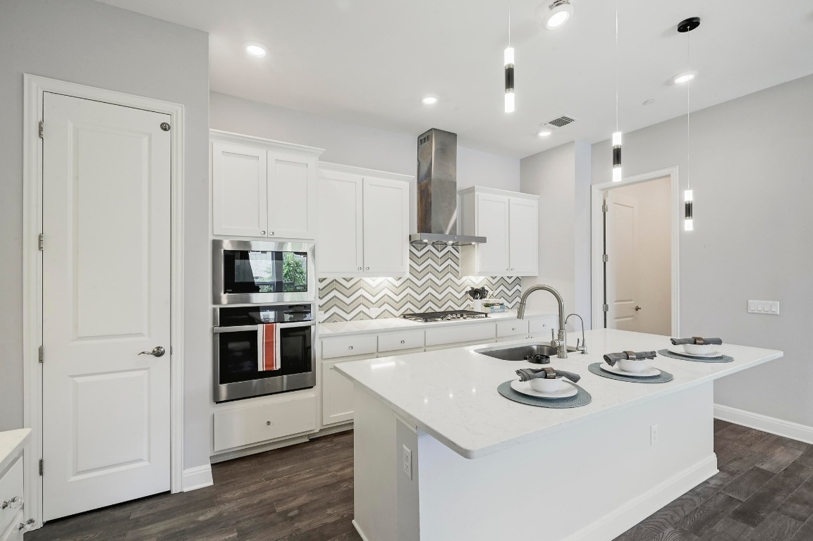 12308 Simmental Drive, Unit 94 Austin, TX 78732 - Photo 7 of 34 a kitchen with stainless steel appliances kitchen island granite countertop a sink and white cabinets with wooden floor
