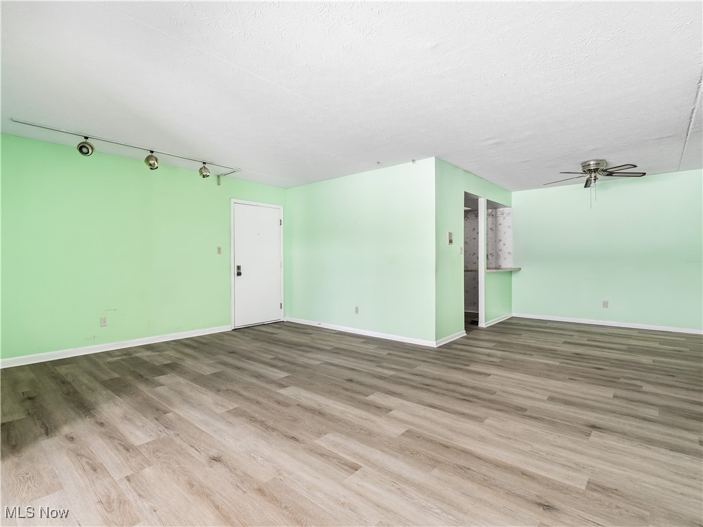 22968 Maple Ridge Road, Unit 103 North Olmsted, OH 44070 - Photo 8 of 25 Empty room featuring a ceiling fan, light wood-style floors, and textured ceiling