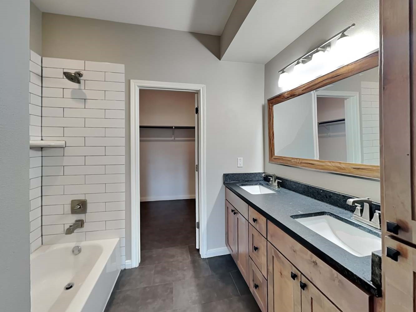 179 Holly Street, Unit 201 Georgetown, TX 78626 - Photo 11 of 17 a bathroom with a granite countertop sink a mirror and a bathtub