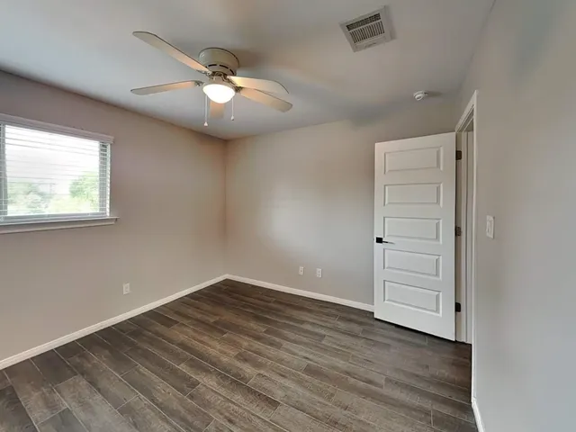 an empty room with wooden floor cabinet and windows