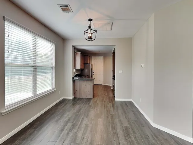 a view of a hallway with wooden floor and a kitchen