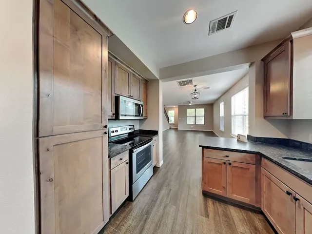 a kitchen with granite countertop a refrigerator stove top oven and sink