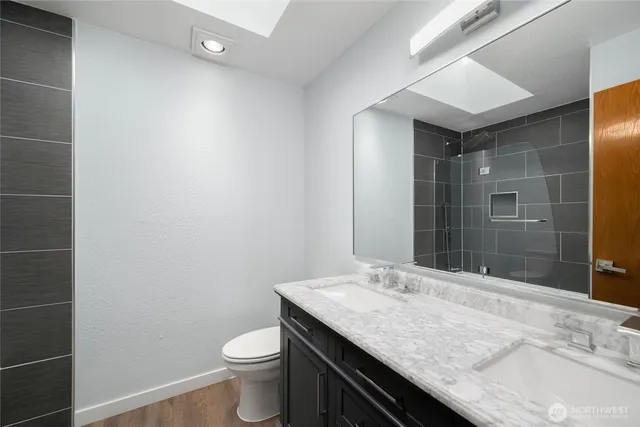 a bathroom with a granite countertop sink a toilet and shower