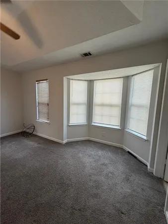 an empty room with a chandelier fan and windows