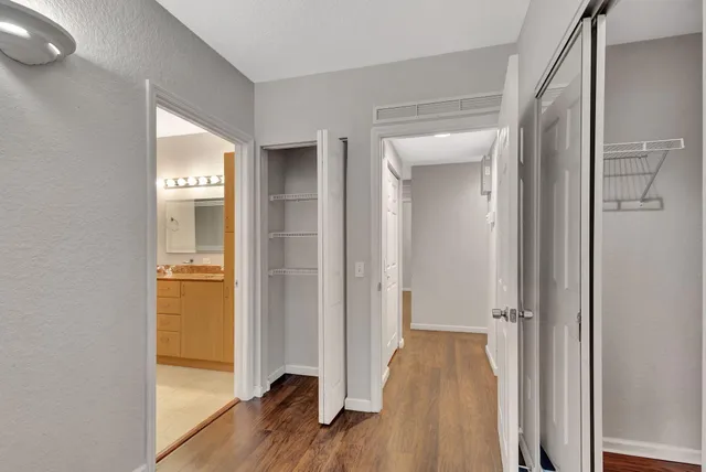 a view of a hallway with wooden floor and a bathroom