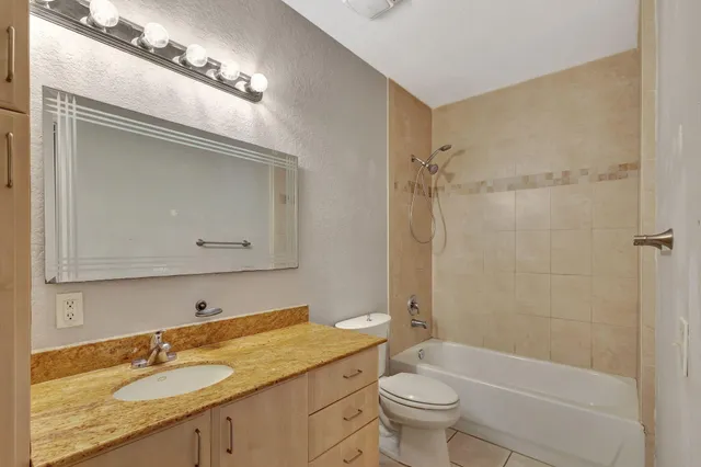 a bathroom with a granite countertop sink a toilet and a mirror