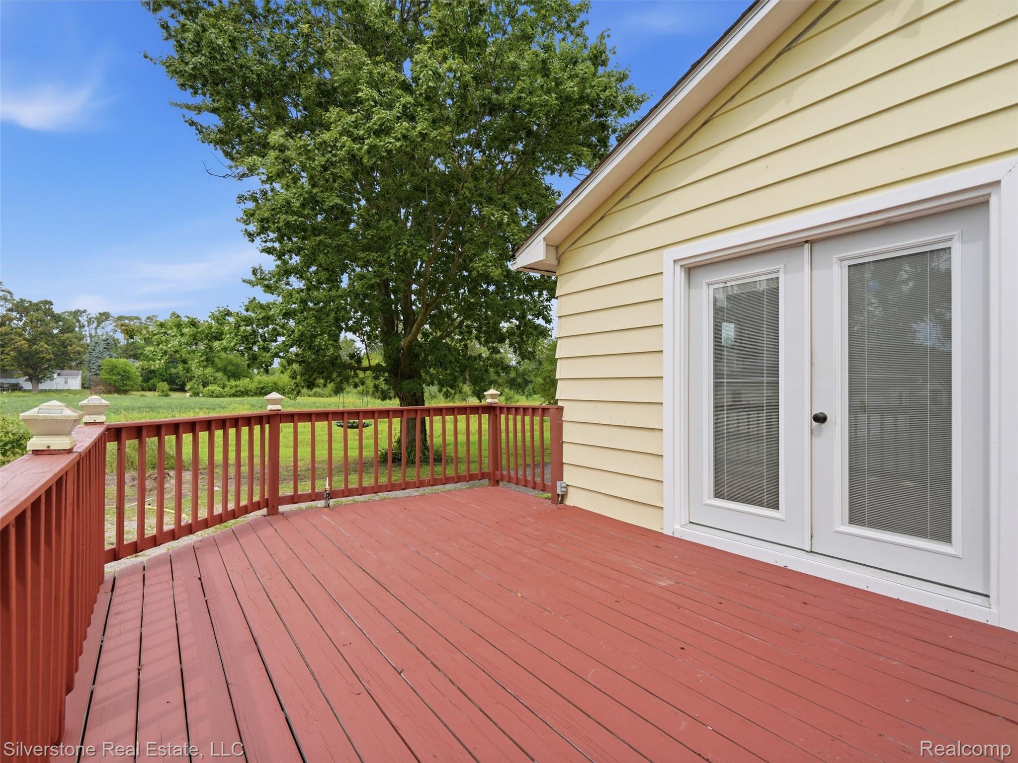 9691 Grames Road Maybee, MI 48159 - Photo 37 of 44 Expansive outdoor deck with red-stained wood flooring and matching railing, complemented by post caps