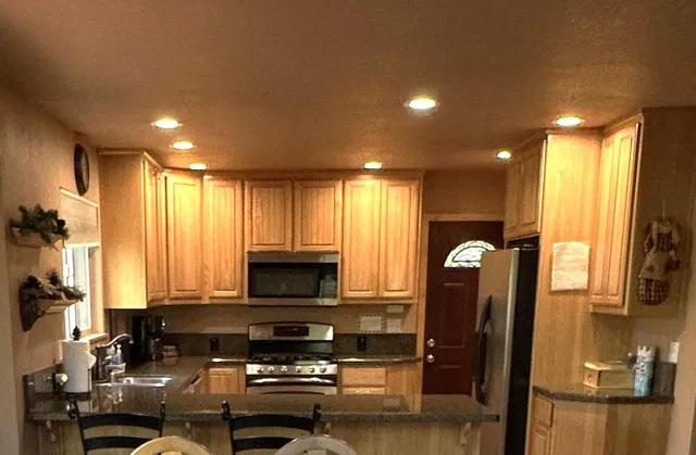 a view of kitchen with stainless steel appliances granite countertop a refrigerator and a stove top oven