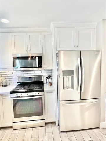 a white refrigerator freezer and a stove sitting inside of a kitchen with cabinets