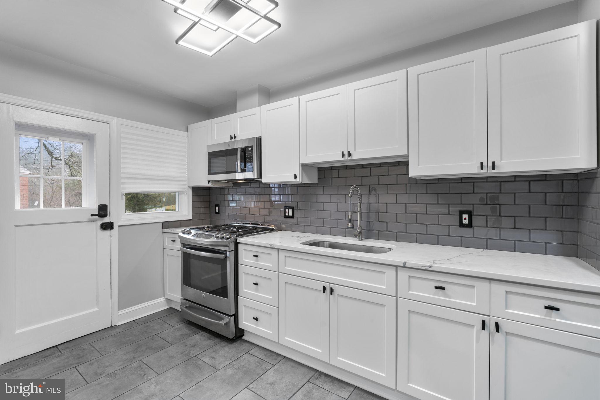 1607 Stonewood Road Baltimore, MD 21239 - Photo 12 of 53 a kitchen with white cabinets stainless steel appliances and sink