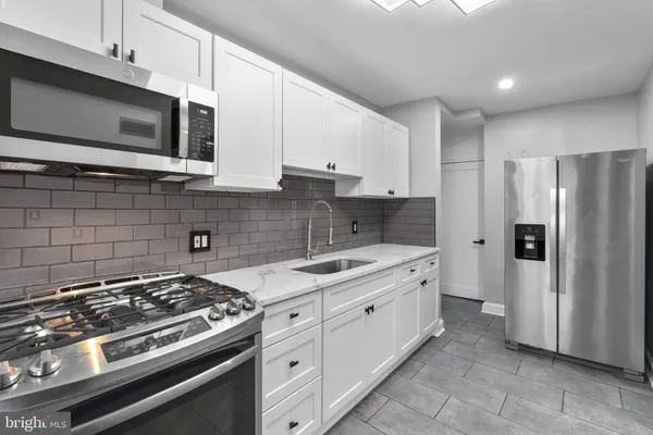 a kitchen with stainless steel appliances a sink a stove a microwave a sink and cabinets