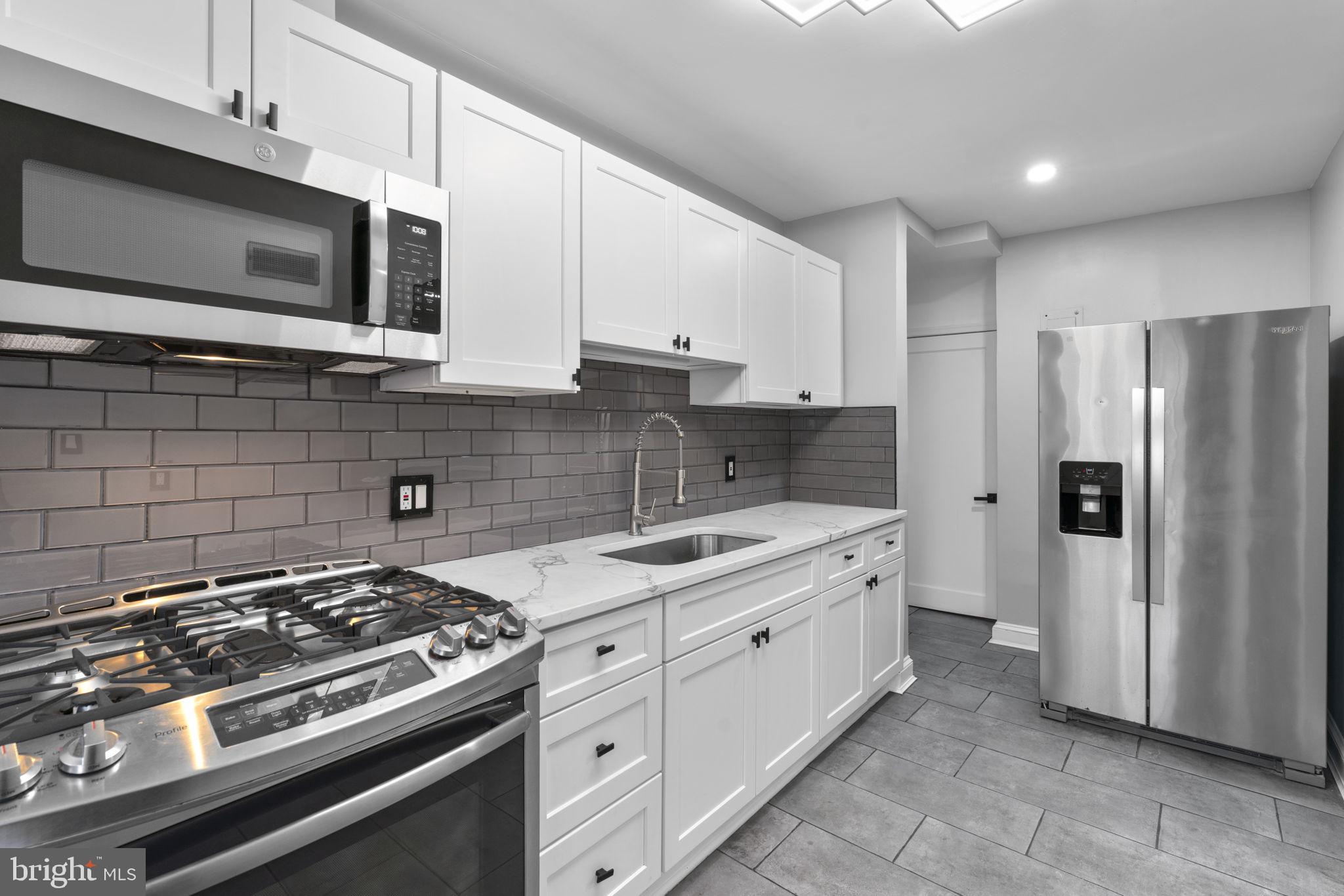 1607 Stonewood Road Baltimore, MD 21239 - Photo 14 of 53 a kitchen with stainless steel appliances a sink a stove a microwave a sink and cabinets