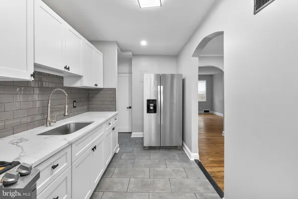 a large white kitchen with stainless steel appliances granite countertop a refrigerator and a sink