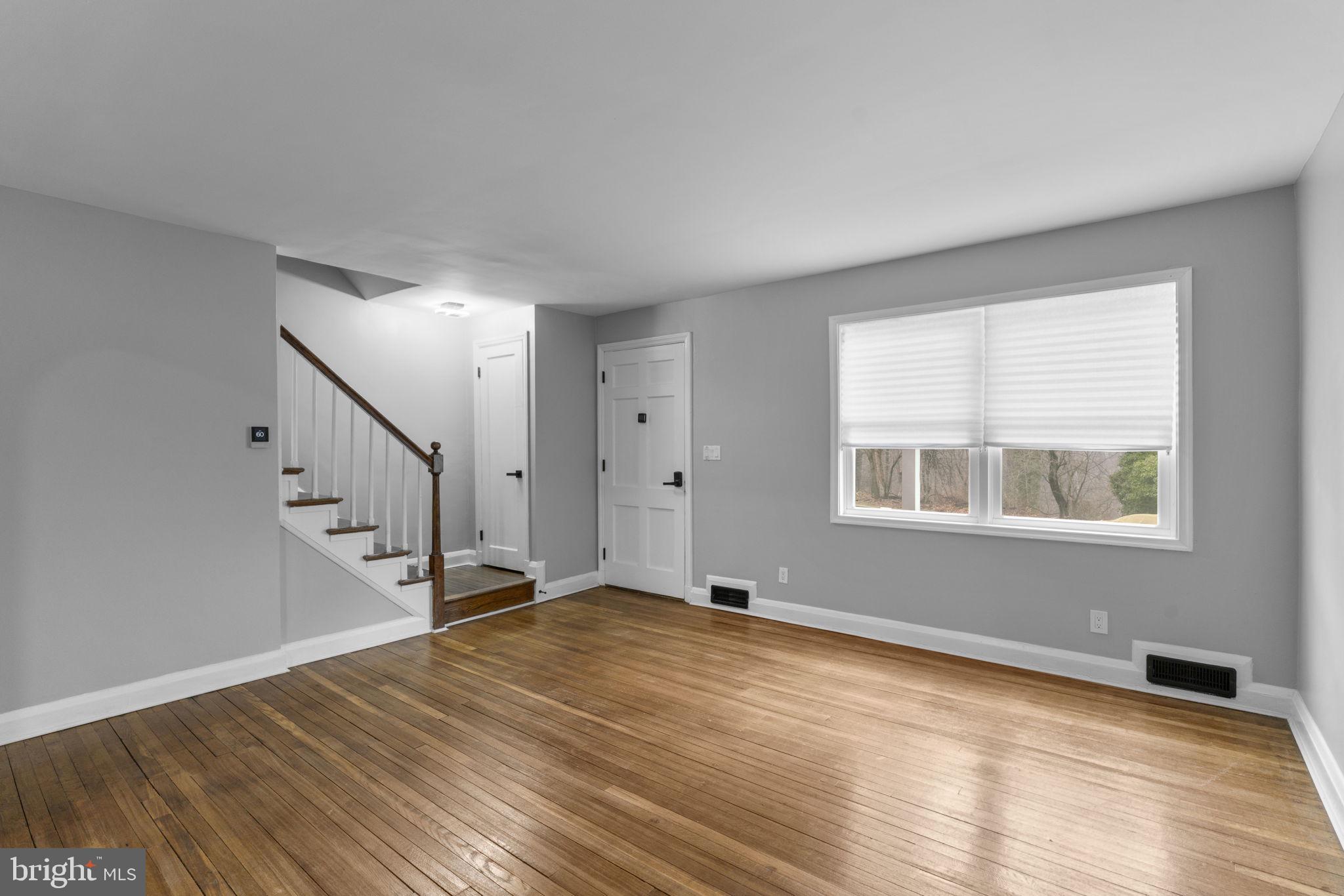1607 Stonewood Road Baltimore, MD 21239 - Photo 5 of 53 a view of an empty room with wooden floor and a window