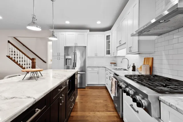 a kitchen with granite countertop a sink a stove refrigerator and cabinets