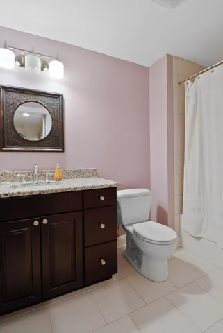 a bathroom with a granite countertop toilet sink and mirror