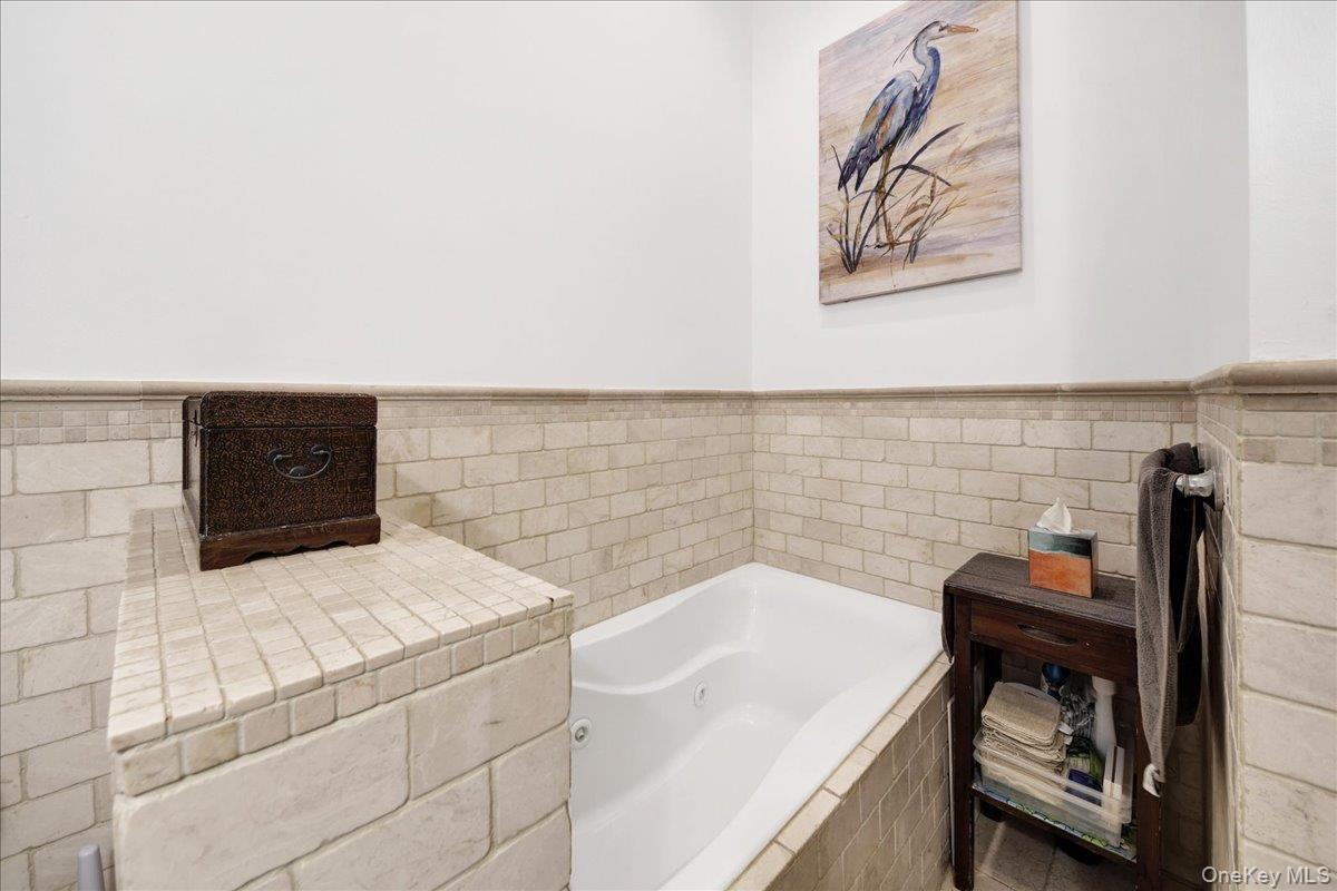 2 Harbor Lane, Unit 102 New Rochelle, NY 10805 - Photo 16 of 30 The bathroom features a built-in tub with tile surround, complemented by subway tile walls
