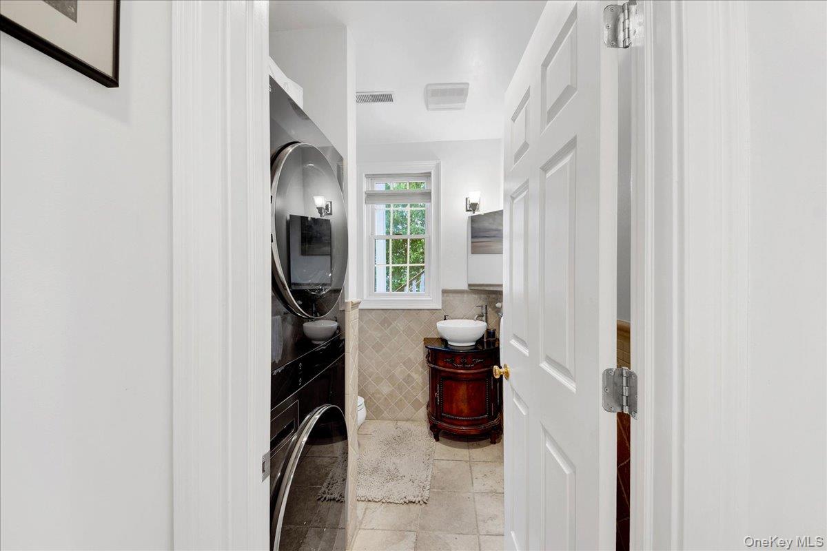 2 Harbor Lane, Unit 102 New Rochelle, NY 10805 - Photo 17 of 30 This space features a stacked washer and dryer unit, a window with natural light, and tiled flooring