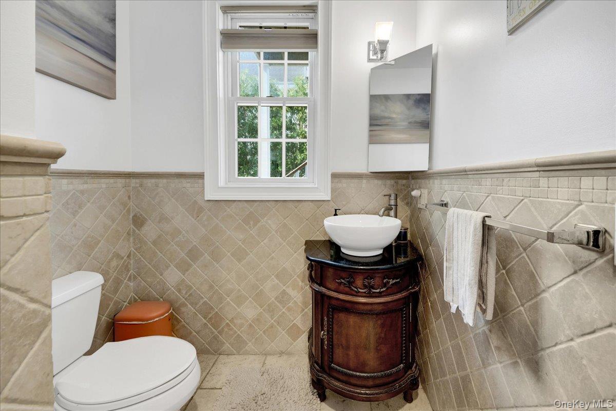 2 Harbor Lane, Unit 102 New Rochelle, NY 10805 - Photo 18 of 30 This 1/2 bathroom features tiled walls and flooring, a window, and a vanity with a vessel sink