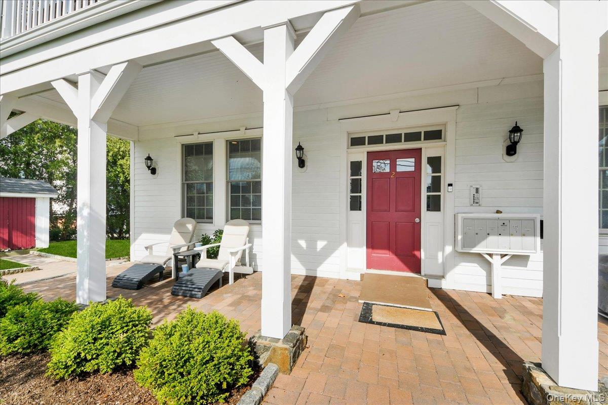 2 Harbor Lane, Unit 102 New Rochelle, NY 10805 - Photo 22 of 30 The property features a welcoming front porch with white columns, a vibrant red entry door with sidelights and transom windows, and exterior wall sconces