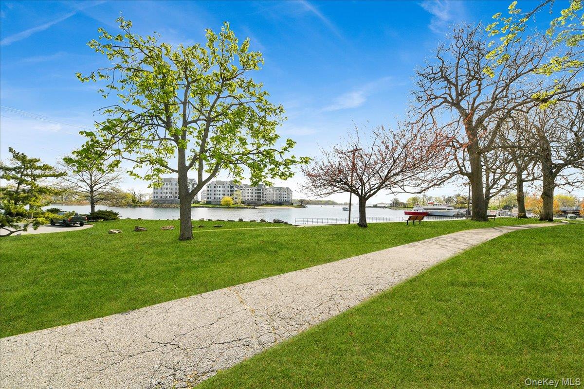 2 Harbor Lane, Unit 102 New Rochelle, NY 10805 - Photo 24 of 30 The property features a landscaped green space with a paved pathway, mature trees, and waterfront views