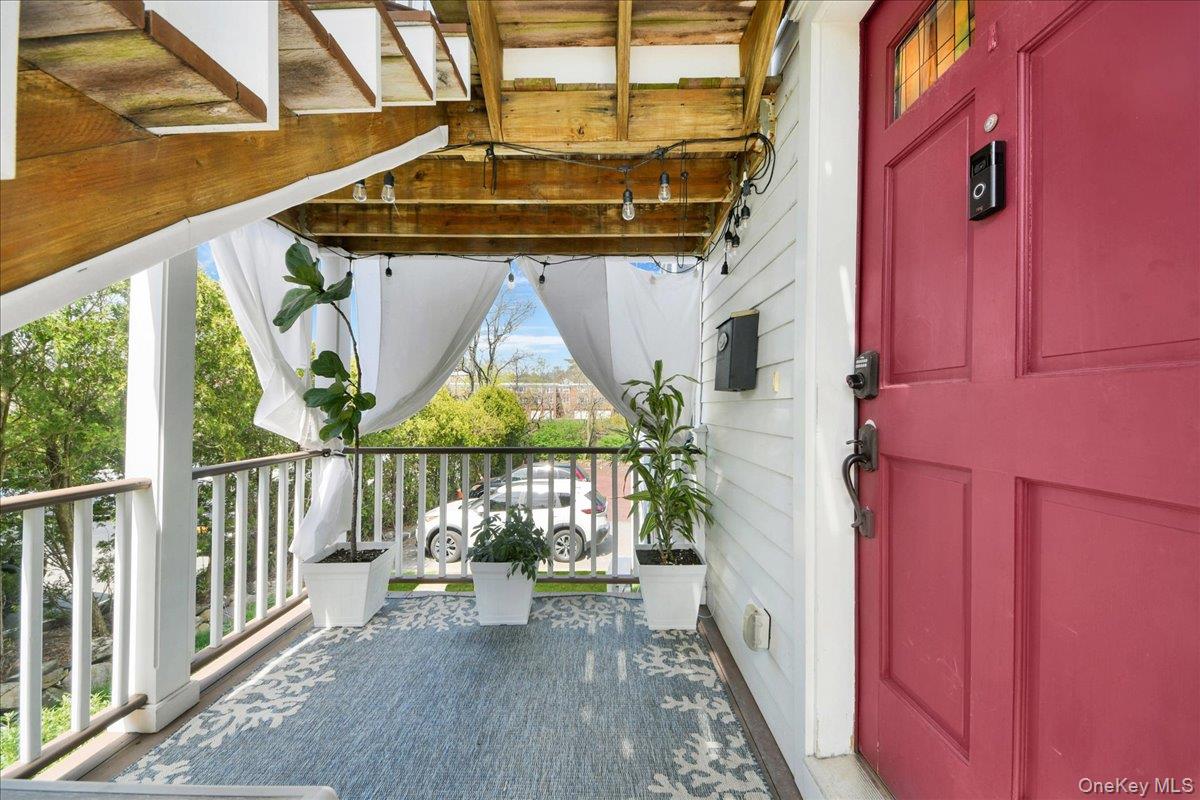 2 Harbor Lane, Unit 102 New Rochelle, NY 10805 - Photo 3 of 30 Inviting front porch featuring a vibrant red entry door, white railings, and a decorative rug