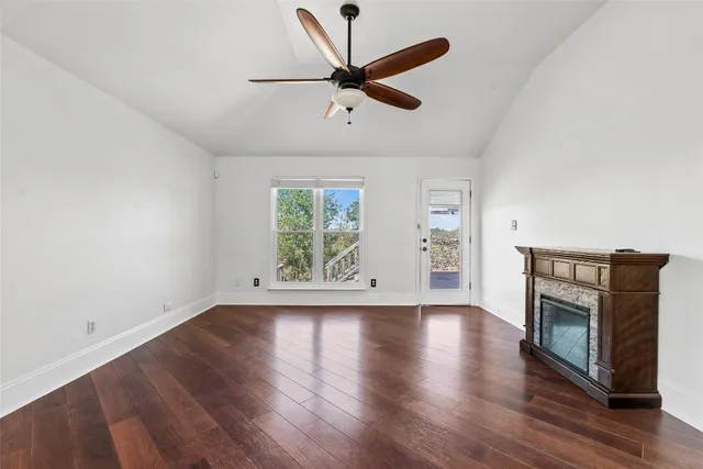 wooden floor in an empty room with a window and a fireplace