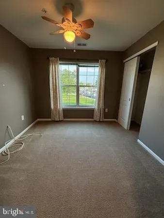 an empty room with windows and fan