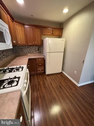 a kitchen with wooden floors and white appliances