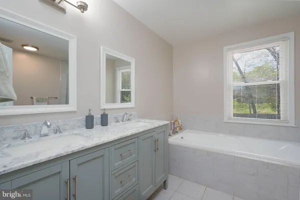 a bathroom with a granite countertop bathtub sink double vanity and mirror