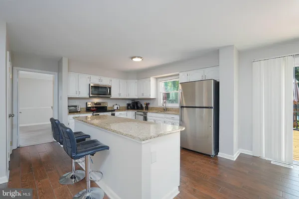 a kitchen with stainless steel appliances granite countertop a refrigerator a stove a sink dishwasher and a refrigerator with wooden floor