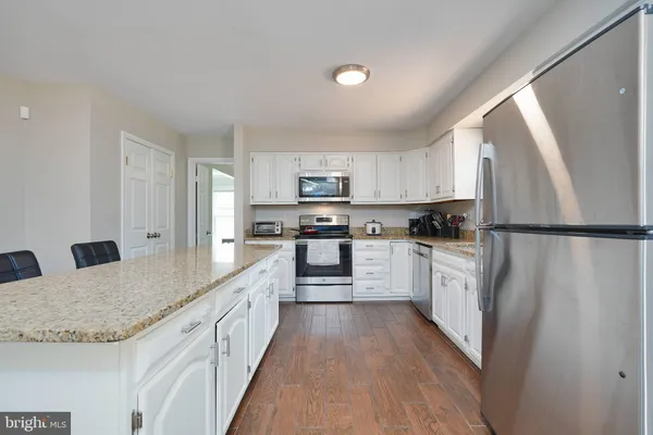 a kitchen with granite countertop a refrigerator stove top oven and sink
