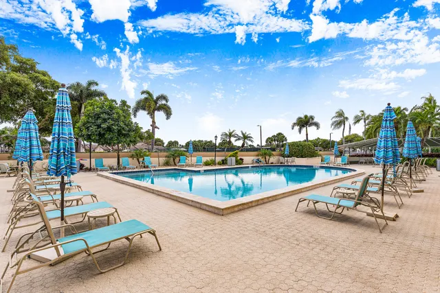 an aerial view of a swimming pool with a yard and outdoor seating