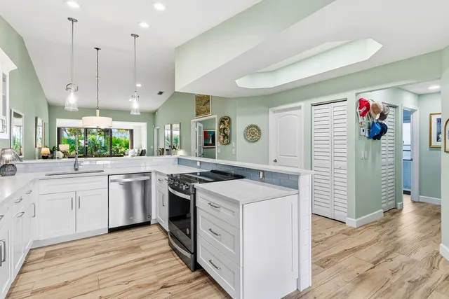a kitchen with stainless steel appliances kitchen island granite countertop a table chairs in it and wooden floors