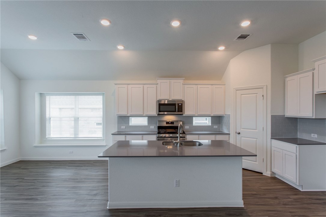 312 Prato Place Georgetown, TX 78628 - Photo 28 of 33 a kitchen with stainless steel appliances granite countertop a stove a sink and white cabinets