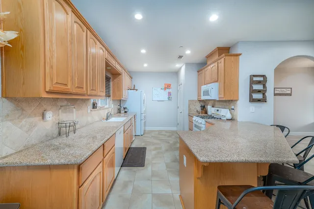 a kitchen with kitchen island granite countertop a sink a counter top space and cabinets