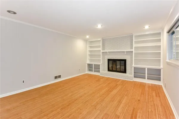 a view of empty room with wooden floor and fireplace